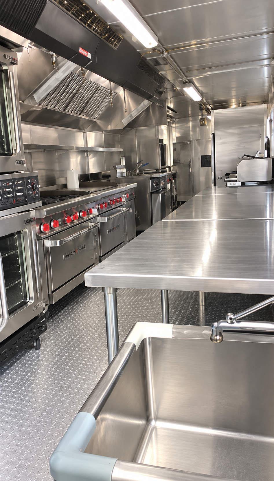 Cooking range, ventilation hood, prep table and sink inside a mobile kitchen
